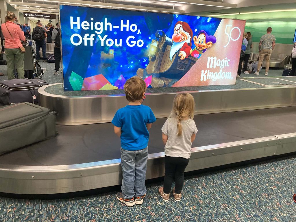 two children waiting at bag claim at orlando airport. 
