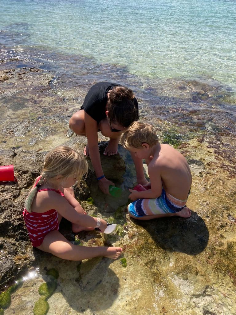one adult and two children playing with sand toys in the ocean