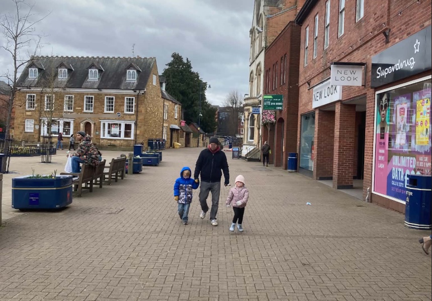 one adult and two children walking down a sidewalk in England